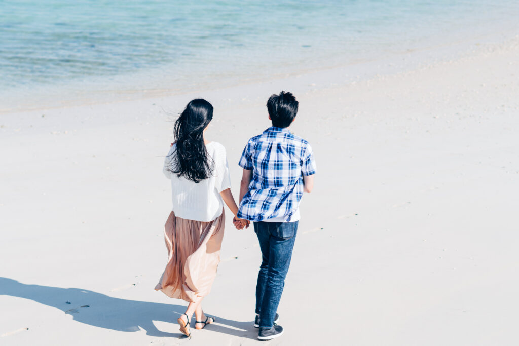 美しい沖縄のビーチを、手をつないで歩くカップル