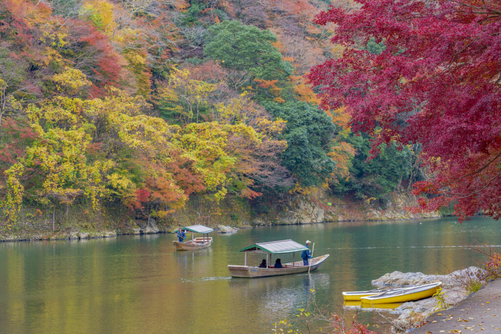秋の嵐山と川を行く舟