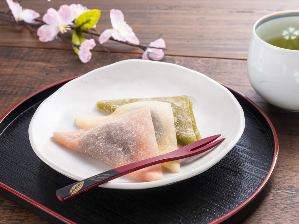 白い丸皿にのせられた桜と抹茶の八つ橋と日本茶