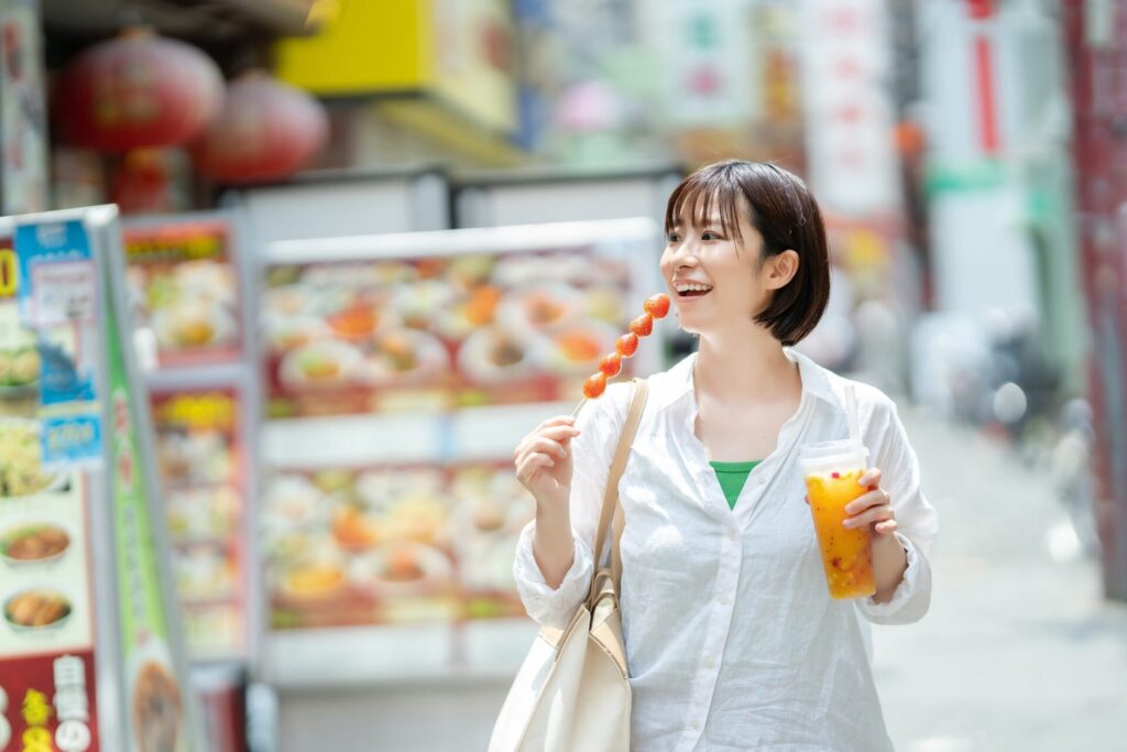 横浜中華街にて食べ歩きを楽しむ女性