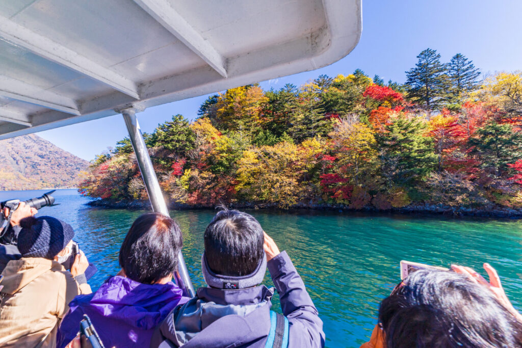 中禅寺湖遊覧船から紅葉を撮影する観光客