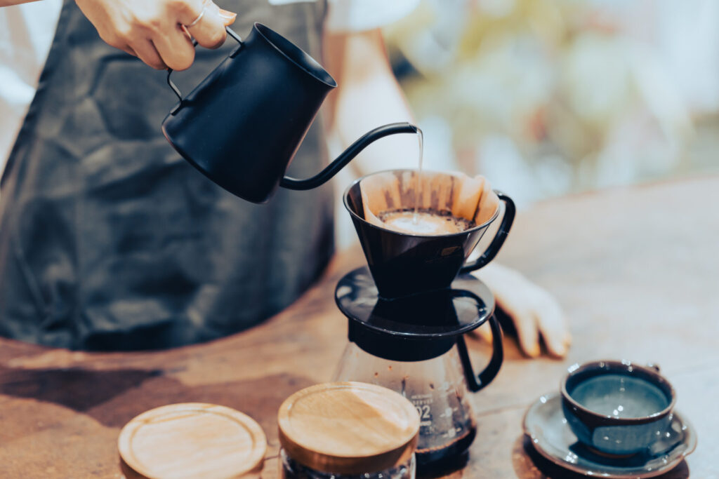 コーヒーケトルでドリップコーヒーをいれる若い女性店員　