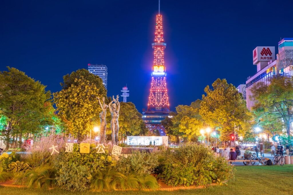 晴れの夜空にライトアップされた札幌テレビ塔と札幌大通公園に集う人々の夜景
