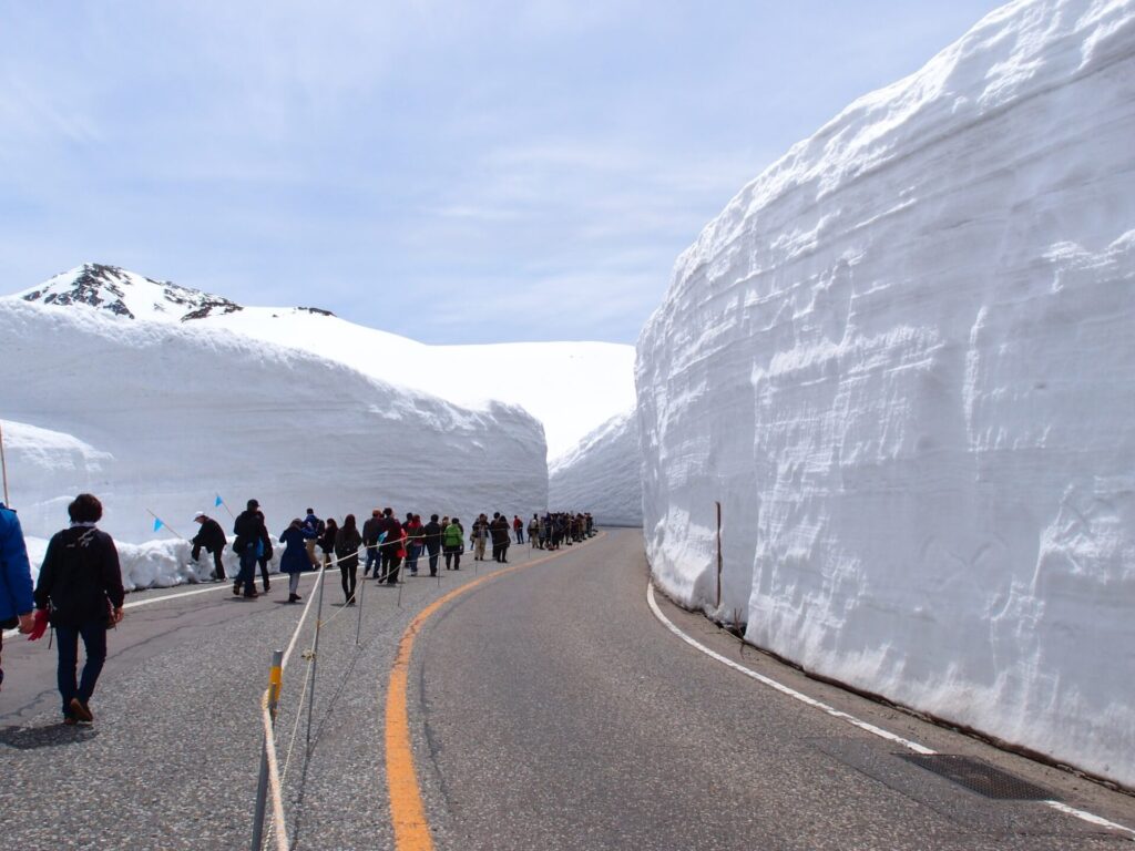 雪の大谷を歩く観光客