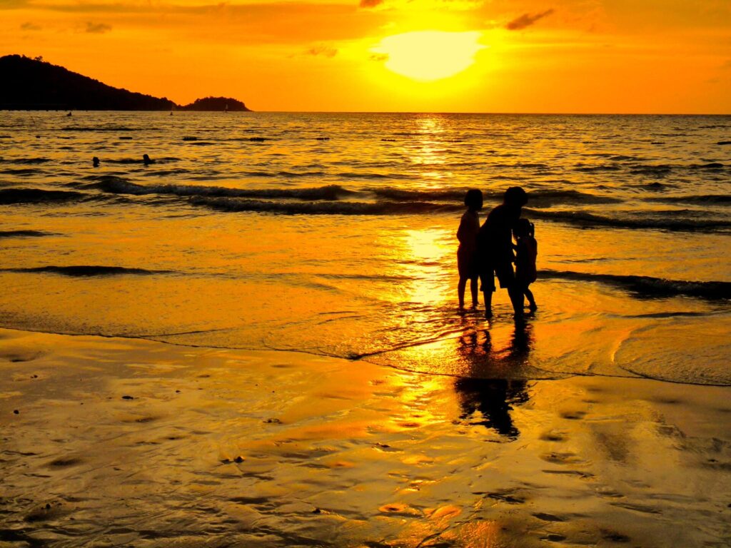 プーケット・パトンビーチの夕暮れの元、砂浜で遊ぶ家族 