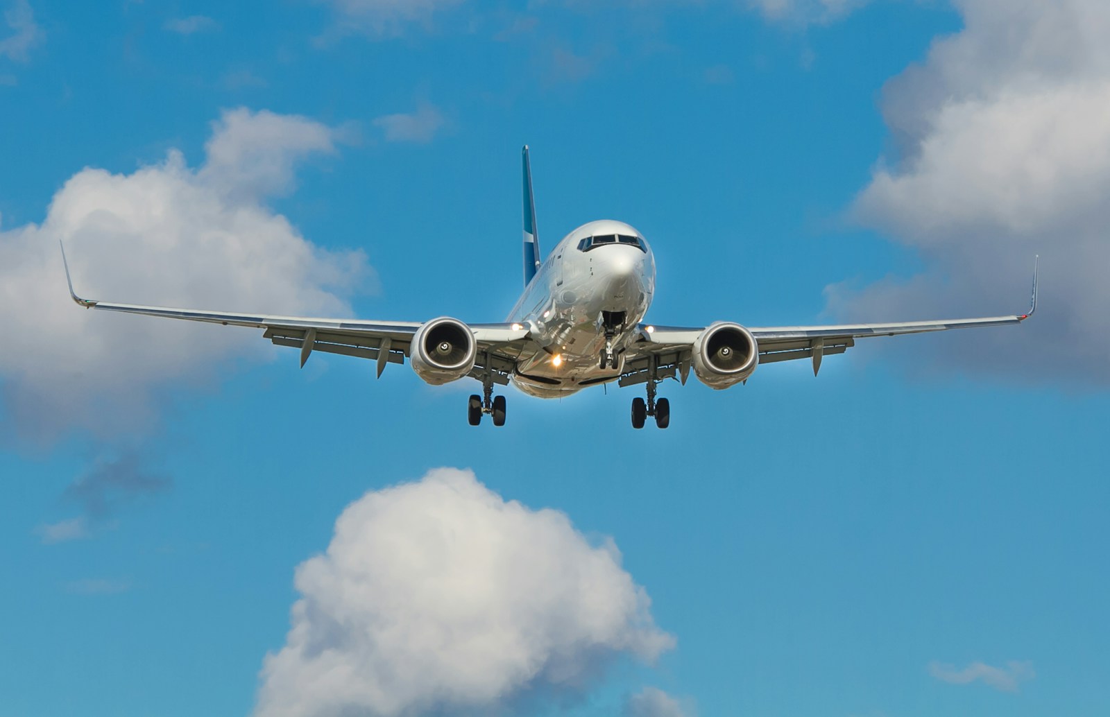 青空と雲の間を飛ぶ飛行機のイメージ