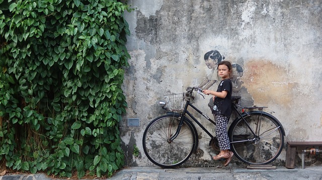 対策KW「壁に描かれた絵の前に立つ自転車に乗った少女」