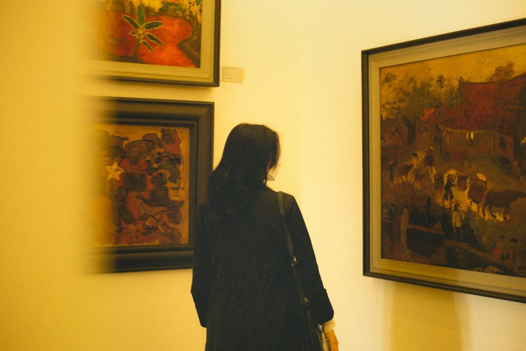 a woman standing in front of some paintings