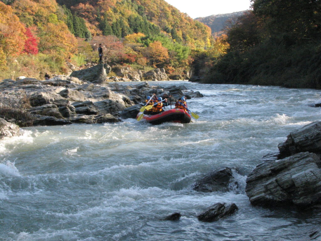 紅葉が美しい11月の長瀞でラフティングを楽しむ観光客