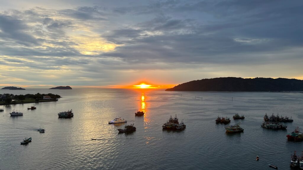 a body of water with boats in it and a sunset in the background